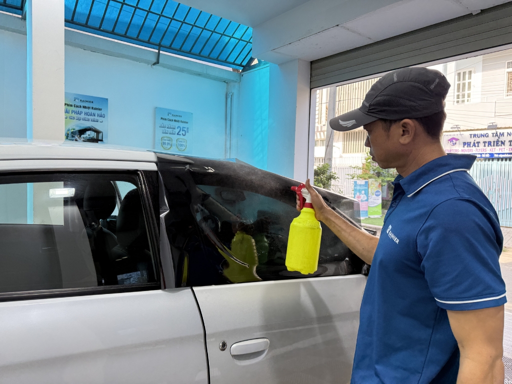 Kỹ thuật viên xịt dung dịch dán lên xe ô tô